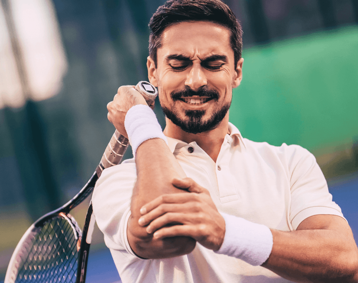Tennis player athlete grimacing in pain with tennis elbow thinking about applying Battle Balm pain relief cream zoomed in 10%