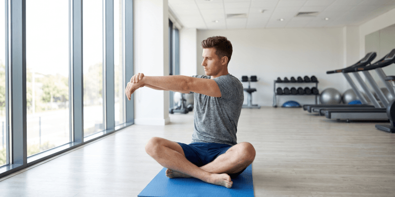 Male performing wrist flexion stretching exercise for forearm extensor muscles after applying Battle Balm all natural topical pain relief cream.