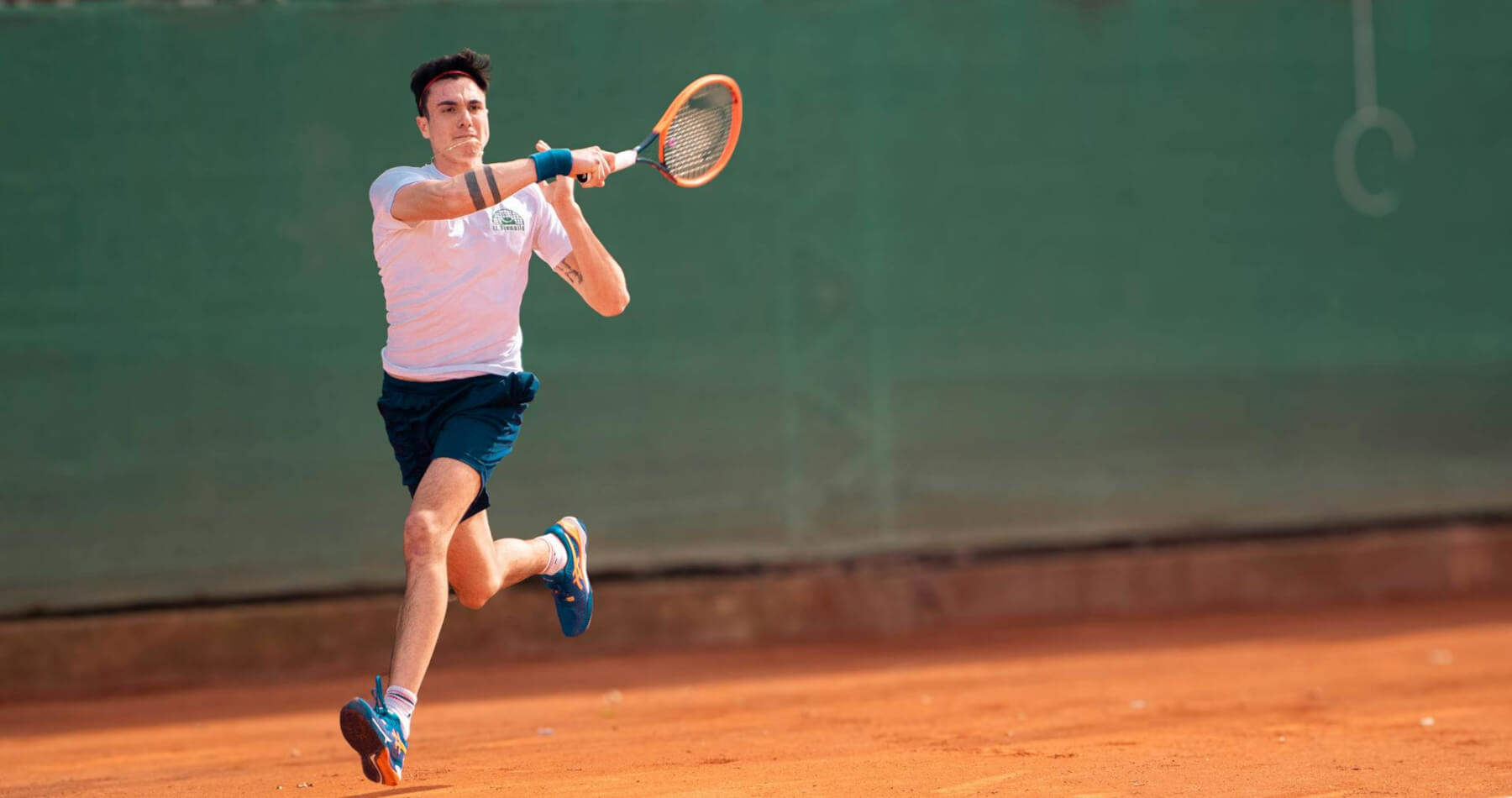Male athlete playing tennis with no lateral epicondylitis pain and hitting a forehand winner. He uses Battle Balm all natural & organic topical pain cream to stay healthy on the tennis court.